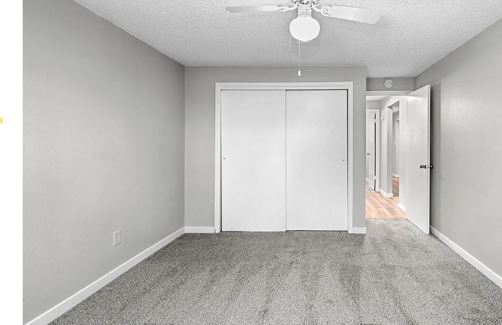 A room with a ceiling fan and a white door.