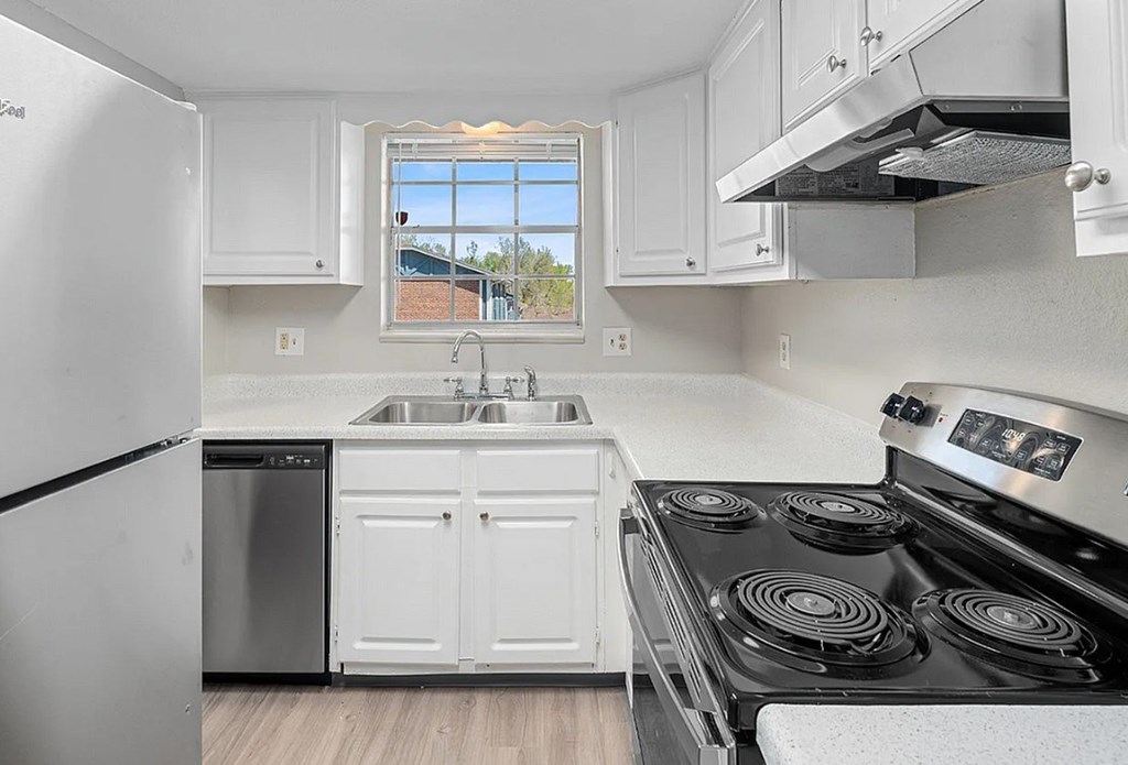 A kitchen with white cabinets and a black stove top.