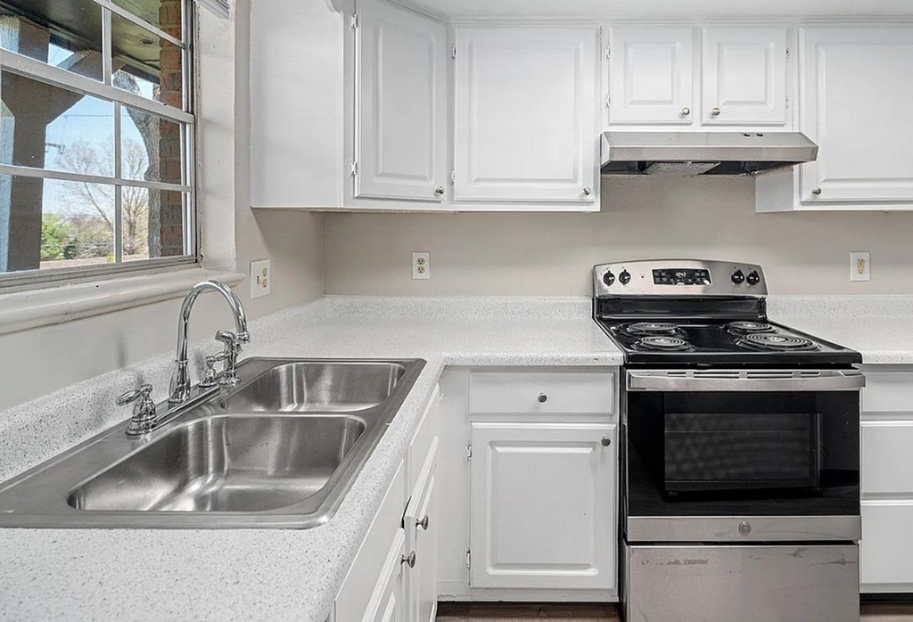 A white kitchen with a stove and sink.