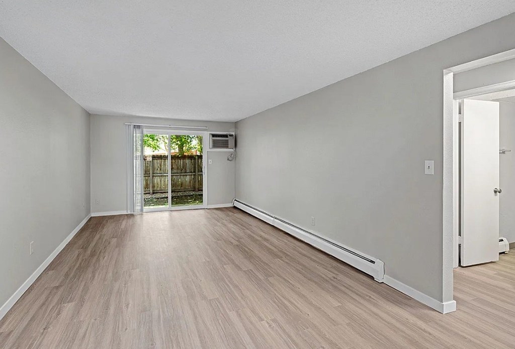 A room with light wood flooring and white walls.