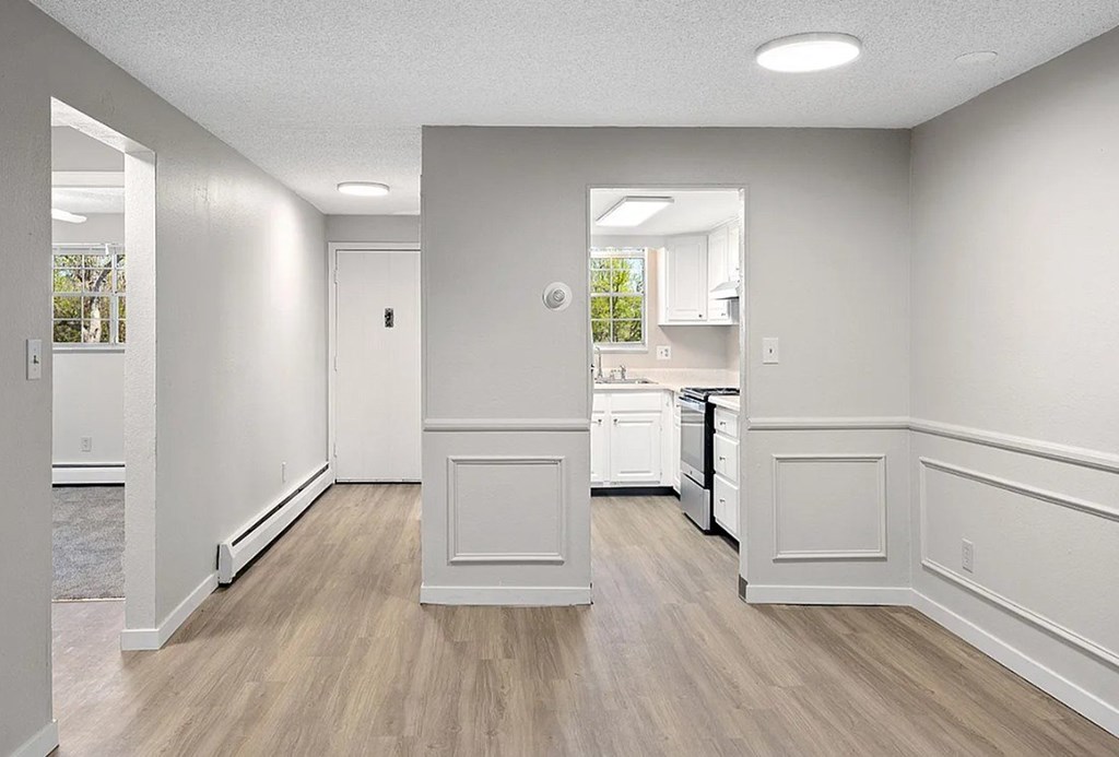 A kitchen area with white cabinets and a wooden floor.