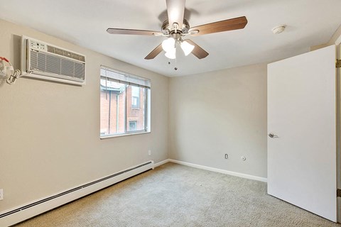 A room with a ceiling fan and an air conditioner unit on the wall.