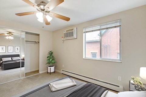 A bedroom with a bed, a ceiling fan, and a window.