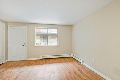 A room with a white door and a window with a view of a building.