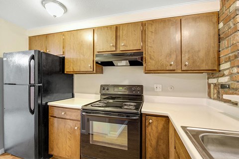 A kitchen with a black refrigerator and stove top oven.