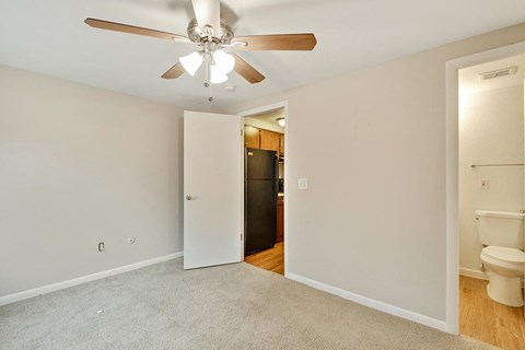 A room with a ceiling fan and a toilet in the corner.