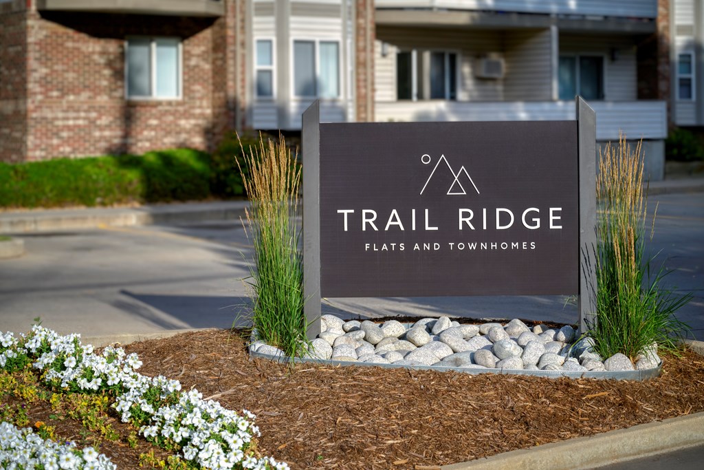 A sign for Trail Ridge Flats and Townhomes is in front of a building.
