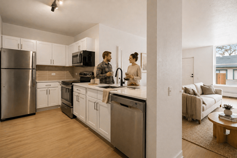 A man and woman are standing in a modern kitchen.