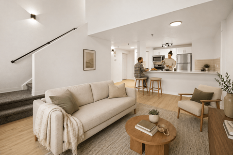 A living room with a couch, a coffee table, and a person in the kitchen.