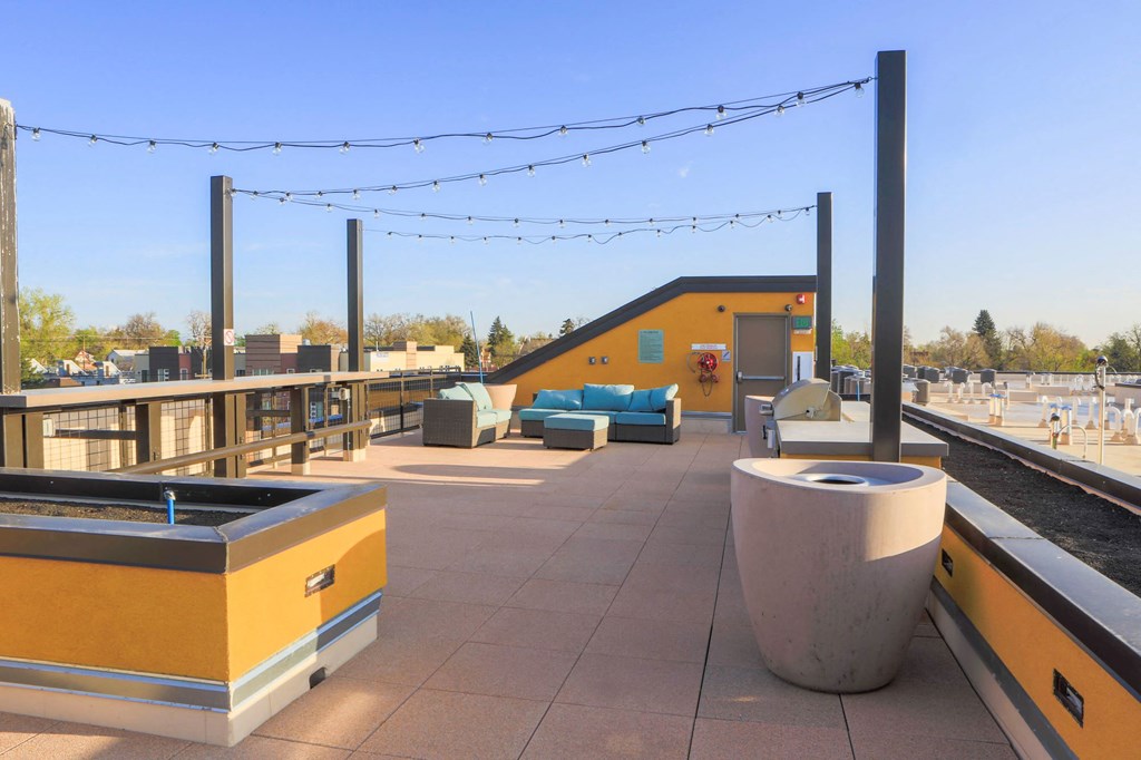a rooftop deck with lounge chairs and a hot tub on a roof