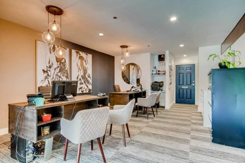 A room with a desk and chairs with a computer on it.