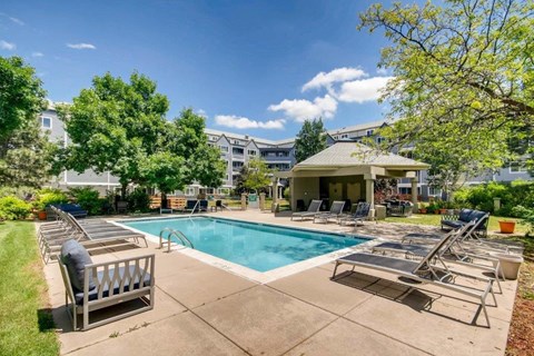 A pool area with sun loungers and a building in the background.