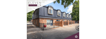 the front of a brick house with a yard and a fence