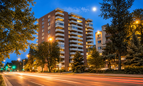 A tall building with a balcony is lit up at night.