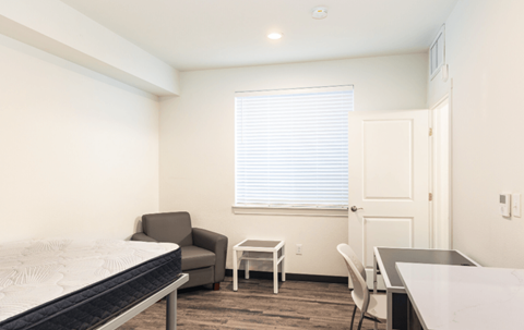 A bedroom with a bed, chair, and table.