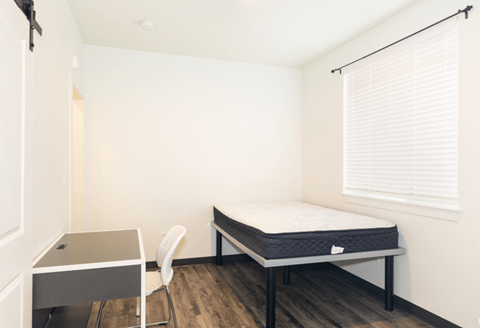 A bedroom with a bed, desk, and chair.