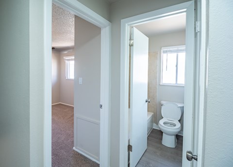 A white bathroom with a toilet and a window.