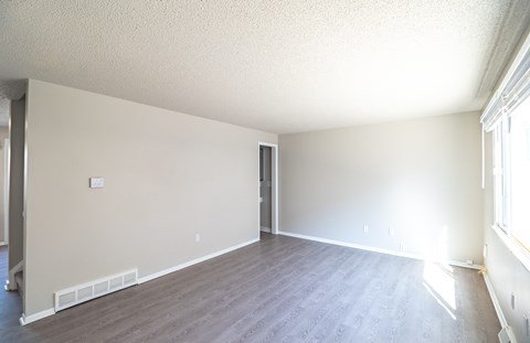 A large empty room with wooden floors and white walls.