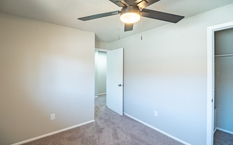 A room with a ceiling fan and carpeted floor.