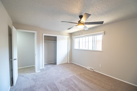 A room with a ceiling fan and carpeted floor.
