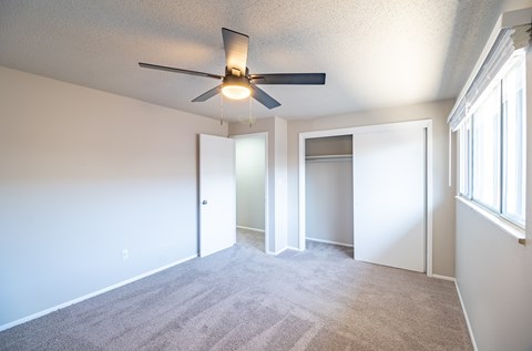 A room with a ceiling fan and carpeted floor.