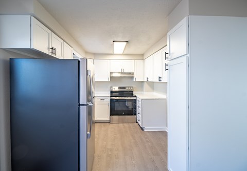 A kitchen with a black refrigerator and white cabinets.