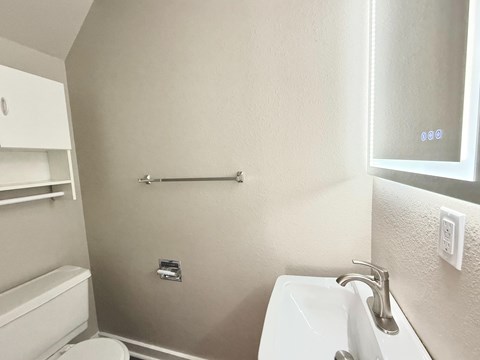 A bathroom with a toilet, sink, and a towel bar.