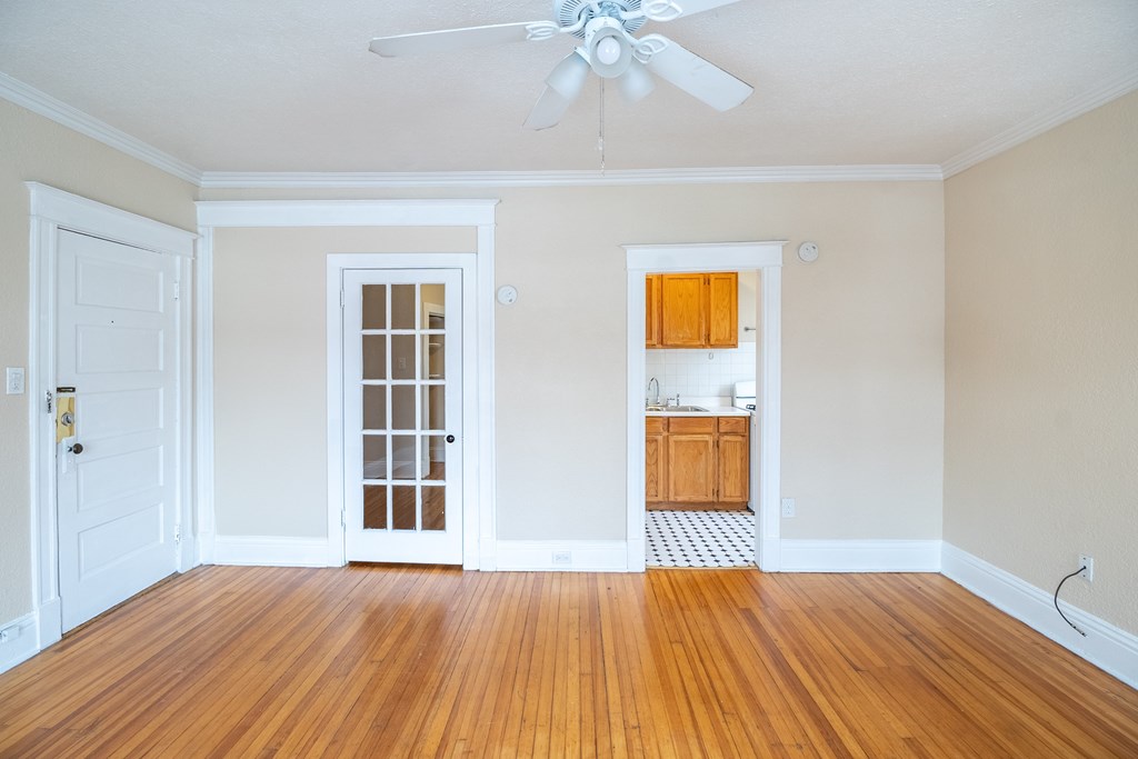 A room with a white door, a window with bars, and a ceiling fan.