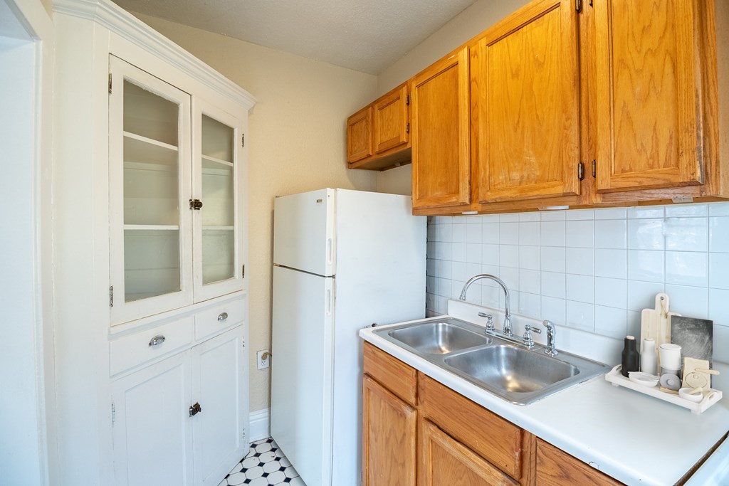 A kitchen with wooden cabinets and a white fridge.
