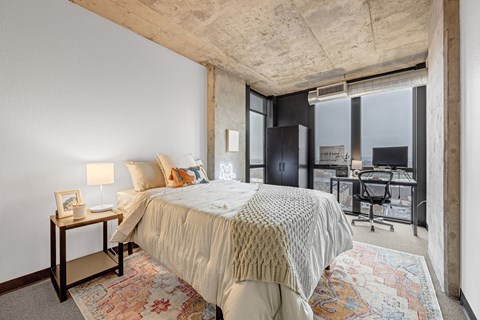 A bedroom with a large bed and a desk with a chair.