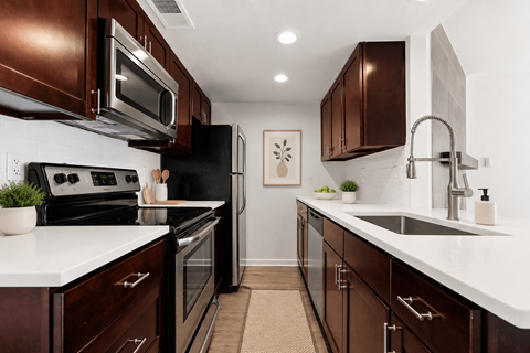 A kitchen with dark brown cabinets and white countertops.
