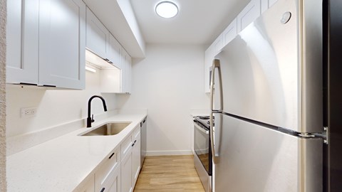 A modern kitchen with a sink, refrigerator, and cabinets.