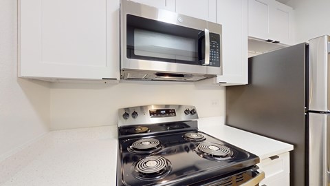 A modern kitchen with a stove, microwave, and refrigerator.