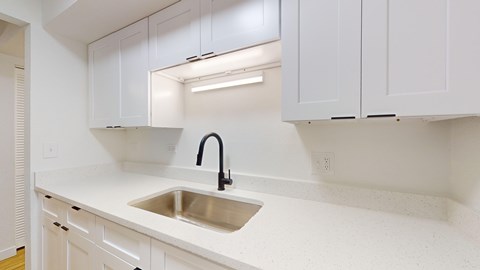 A kitchen with white cabinets and a stainless steel sink.