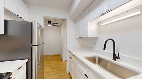 A kitchen with a black fridge and a black faucet.