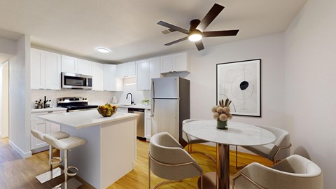 A modern kitchen with a white island and a dining table set for four.