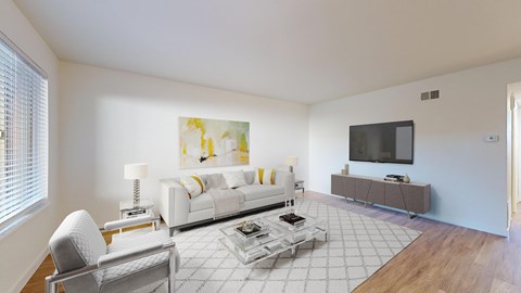 A modern living room with a white sofa, a grey armchair, a coffee table, and a television.