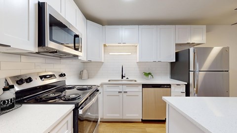A modern kitchen with white cabinets and stainless steel appliances.