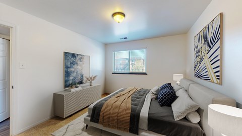 A bedroom with a bed, a bench, and a painting on the wall.