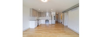 A kitchen with white cabinets and a wooden floor.