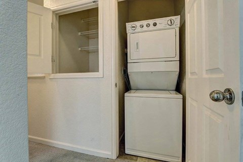 A white dishwasher is stacked on top of a white dryer in a small space.