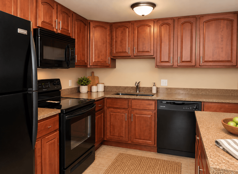 A kitchen with black appliances and wooden cabinets.