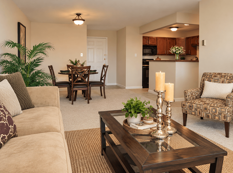 A living room with a brown couch, a wooden coffee table, and a dining table with chairs.
