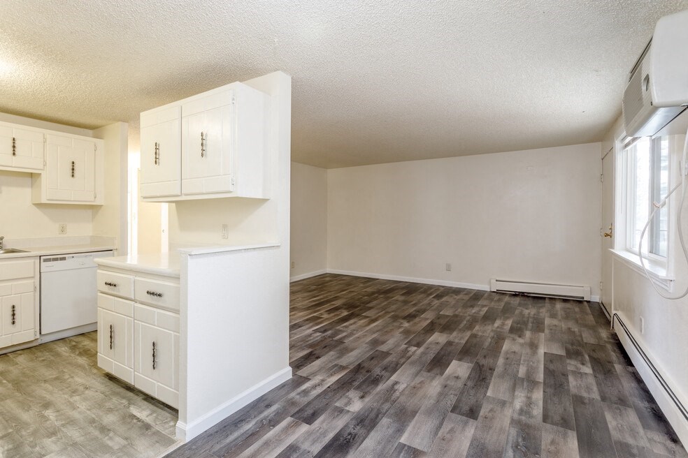 an empty kitchen and living room with white cabinets and white appliances