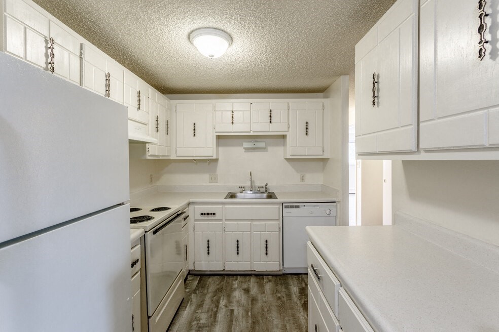 an empty kitchen with white cabinets and white appliances