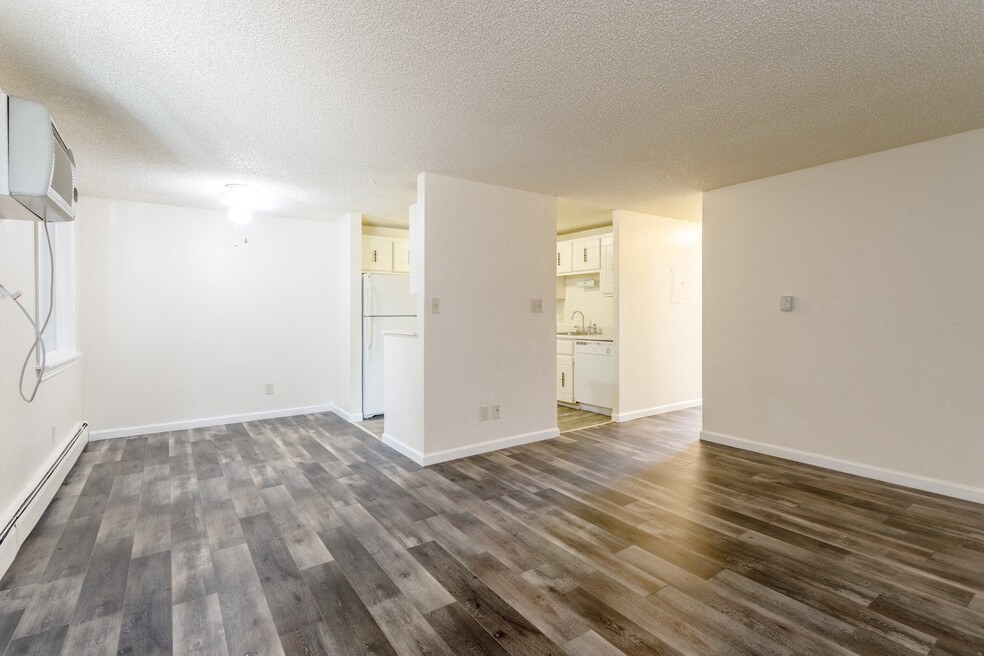 the living room and kitchen of an apartment with wood flooring