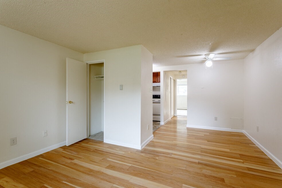 the living room and dining room of an empty apartment with wood flooring