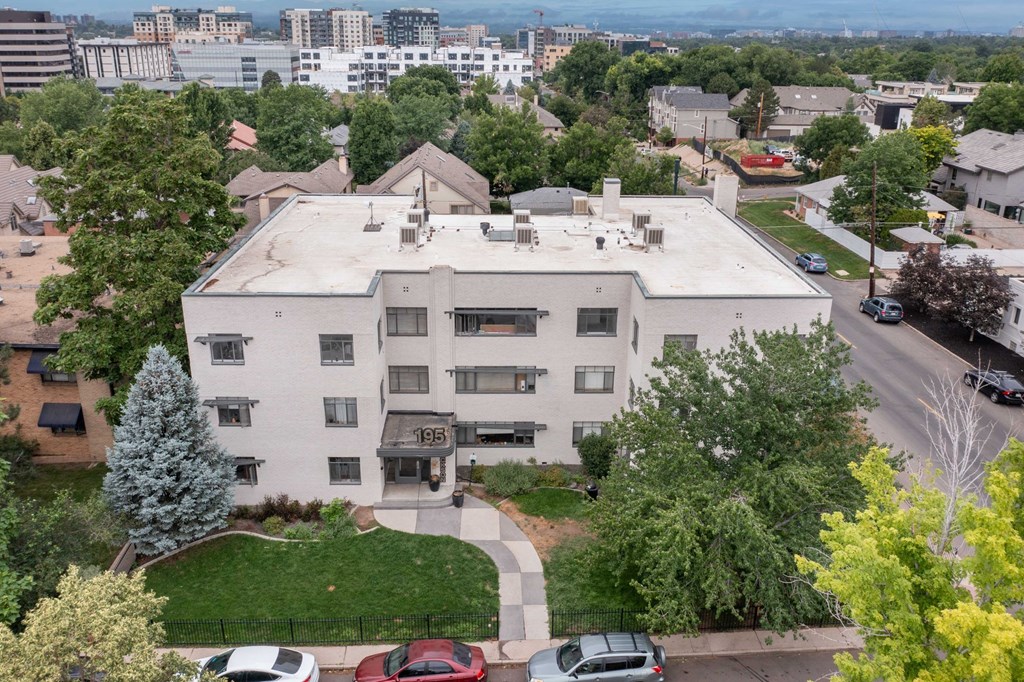 an aerial view of a white building with cars parked in front of it