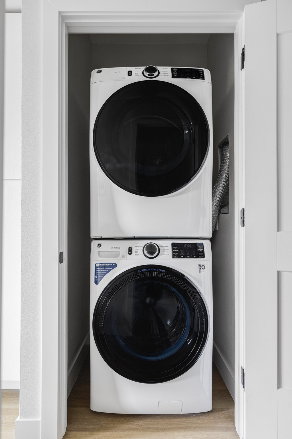 Two white front load washing machines in a small white cabinet.