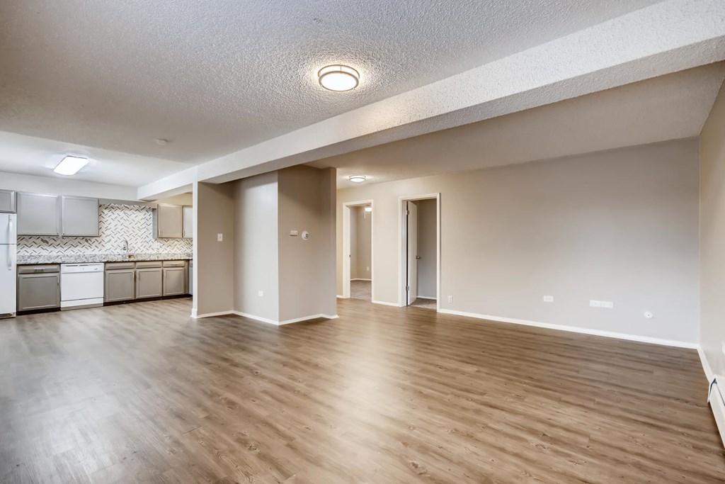 A spacious room with wooden flooring and white walls.